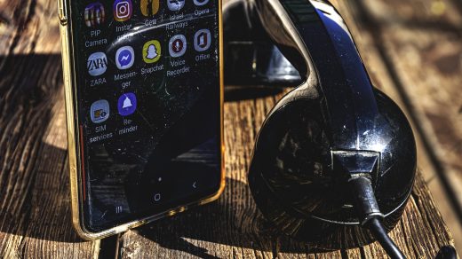 Alter Telefonhörer liegt auf einem Tisch neben einem aufrecht stehenden Smartphone