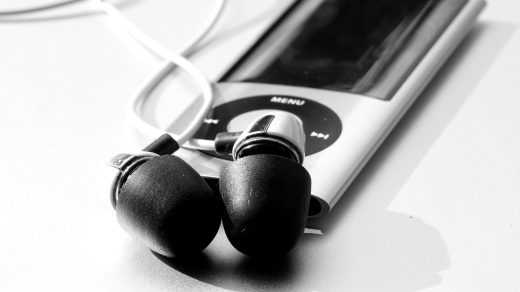 Auf einem Tisch liegt ein MP3-Player mit daran angeschlossenen Kopfhörern.